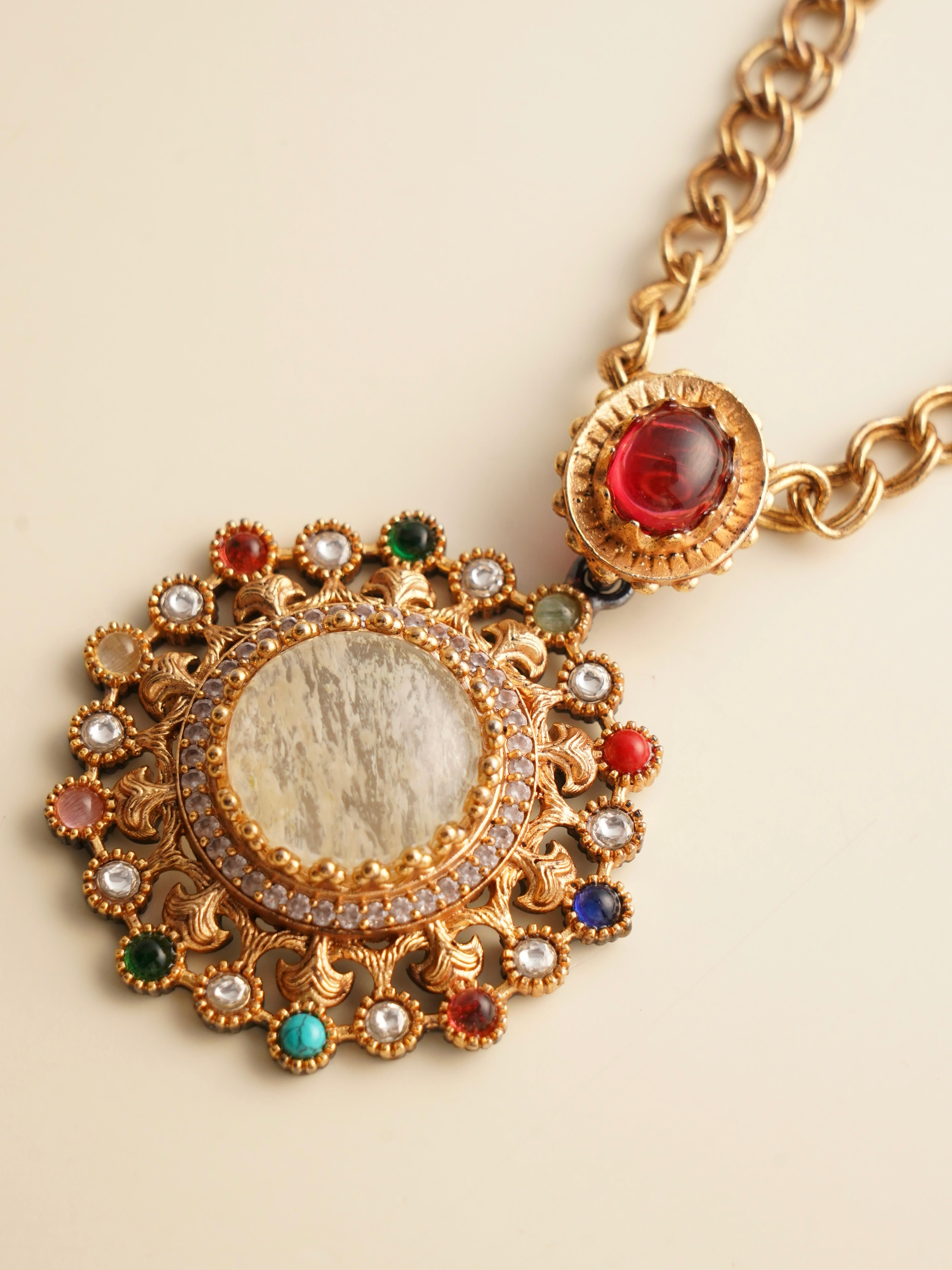 Angled view of navratna pendant and matching earrings with gold-tone finish